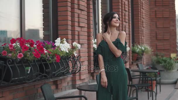 Portrait of young beautiful girl at sunset on the background of old houses. attractive young woman smiling and posing for the camera. — Stock Video