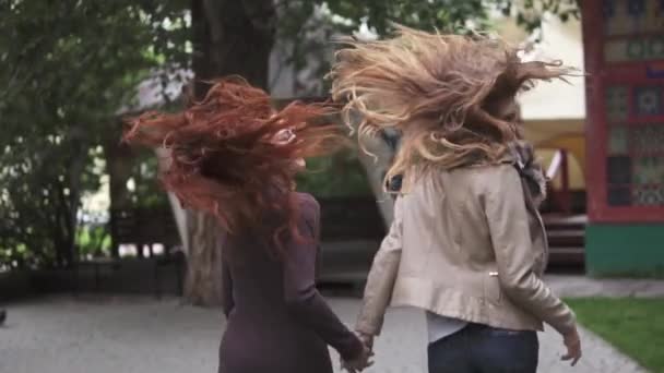 two crazy redheads girlfriends having fun, frolic and jump. the view from the back. slow motion