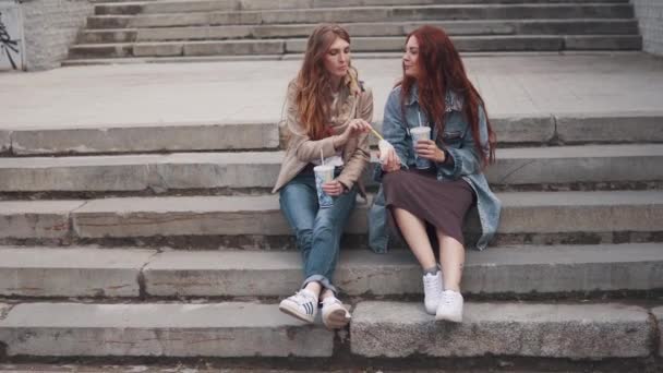 Meisjes eten fastfood zittend op de stappen in de stad — Stockvideo