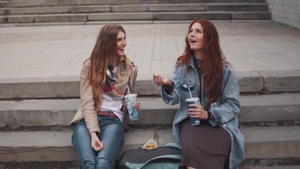 Flickvänner äter snabbmat och busar runt. flicka kastar mat och försöker fånga den i munnen — Stockvideo