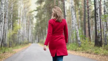 sonbahar Park, yürüyen genç kadın şakacı döner ve kameraya benziyor. çekici kız mevsimlik giyim