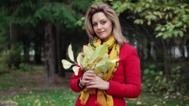 güzel bir genç kadın, bir sonbahar ormanındaki yakın çekim portresi. Kız sararmış yapraklar onun elinde tutuyor