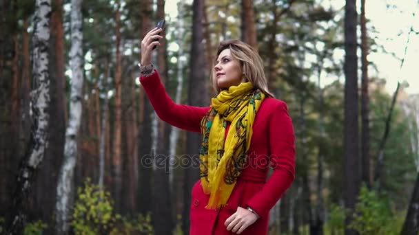 秋の公園を歩いている赤いコートの女性。暖かい秋の午後を楽しむ美少女 — ストック動画