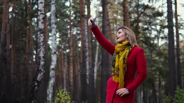 Fiatal nő egy piros kabátot, séta egy őszi park. gyönyörű lány élvezi a meleg őszi délután — Stock videók