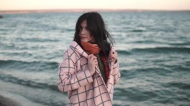 Sahilde güzel bir genç kadının portresi. Kız açık havada sonbahar paltolu