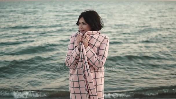 Портрет молодой женщины, которая прячет пальто от осеннего ветра. Медленное движение — стоковое видео