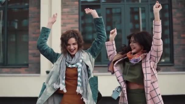 Twee zorgeloos jonge vrouwen veel plezier en dans op straat. vriendinnen veel plezier samen. meisjes lopen in de herfst stad. Slow motion — Stockvideo