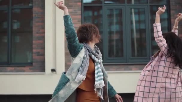 Deux jeunes femmes insouciantes s'amusent et dansent dans la rue. copines s'amusent ensemble. les filles marchent dans la ville d'automne. Mouvement lent — Video