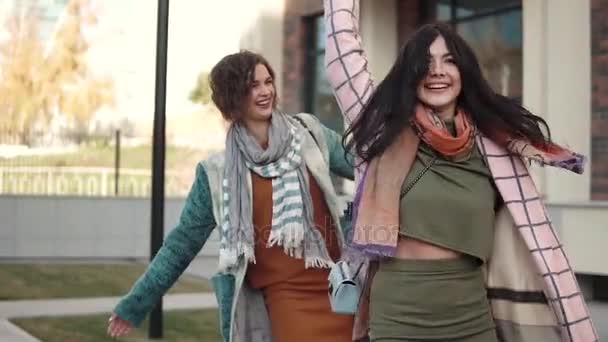 Duas mulheres jovens brincando e se divertindo andando na rua. Os amigos passam tempo juntos. Movimento lento — Vídeo de Stock