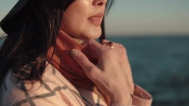Sahilde genç bir kadın portresi. Kız gülümseyerek ve su kamera poz şapka ve sonbahar ceket.