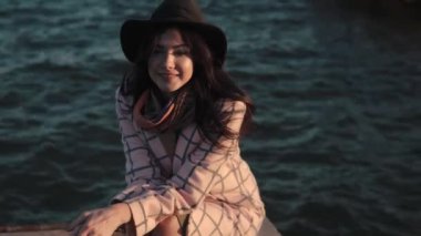 Sahilde genç bir kadın portresi. Kız gülümseyerek ve su kamera poz şapka ve sonbahar ceket.
