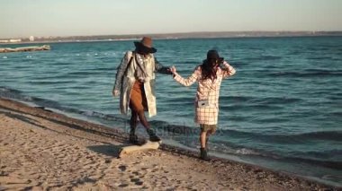 arkadaşlarım el ele tutuşup batımında sahilde yürümek. kızlar sıcak bir sonbahar günü tadını çıkarıyor