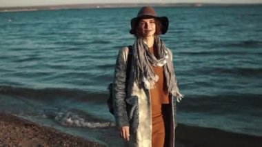 denize karşı sonbahar paltolu sevimli kız portresi. kameraya poz ve gülümseyen kız