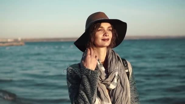 Bella giovane donna cammina lungo la costa, sorridendo e godendo della calda giornata autunnale . — Video Stock