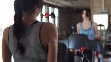 genç kadın spor salonunda egzersiz temiz su içme. bir kız bir koşu bandı üzerinde yürüyor