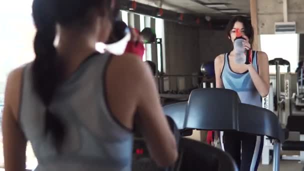 Mujer joven bebiendo agua limpia durante un entrenamiento en una cinta de correr — Vídeos de Stock