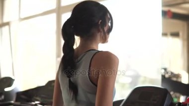 genç kadın spor salonunda bir koşu bandı üzerinde yürür. spor salonunda kardiyo egzersizleri