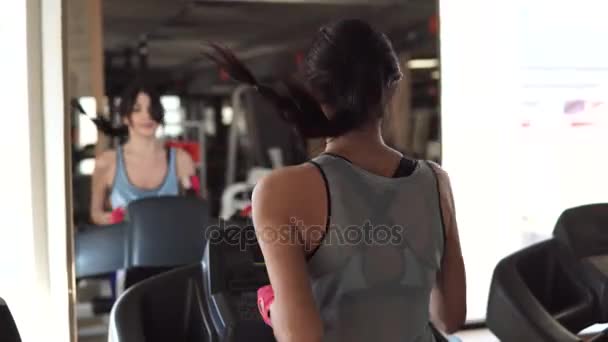 Giovane donna corre su un tapis roulant in palestra. la vista dal retro — Video Stock