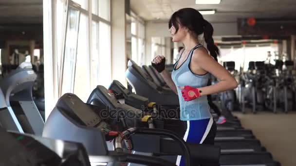 Young sporty girl running on the treadmill at the gym — Stock Video