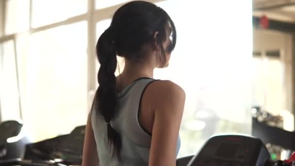 Ung kvinna går på ett löpband på gymmet. konditionsträning i gymmet — Stockvideo