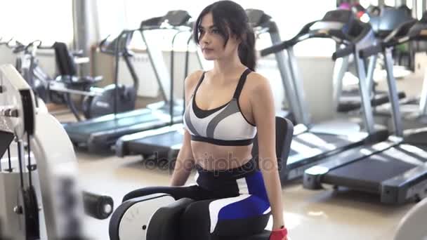 Sportswoman does exercises on buttocks and a back part of a femur on a simulator in an exercise room — Stock Footage Sportswoman does exercises on buttocks and a back part of a femur on a simulator in an exercise room Stock Video