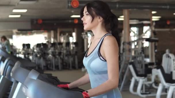 Jonge vrouw loopt op een loopband in de sportschool. cardio-oefeningen in de sportschool — Stockvideo