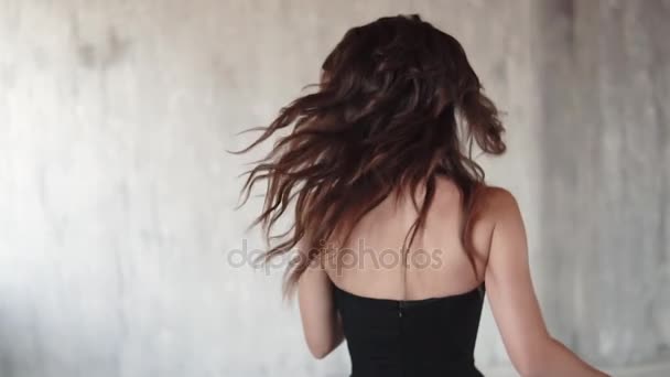 Alegre chica despreocupada enciende la cámara y sonríe suavemente. retrato de una joven con un vestido negro. una chica con ojos humeantes. cámara lenta — Vídeos de Stock