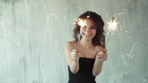 Cheerful girl holding in the hands of sparklers and laughing. the young woman at the party. the festive mood. slow motion — Stock Video
