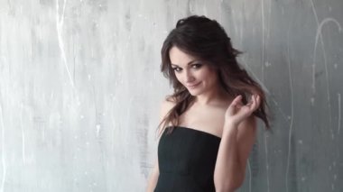 sevimli kız gülümseyerek ve kameraya poz siyah elbiseli. akşam makyaj ve dumanlı gözler ile genç bir kadın portresi