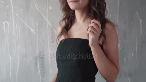 Retrato de una hermosa joven con un vestido negro. chica con maquillaje de noche sonriendo y mirando a la cámara — Vídeos de Stock