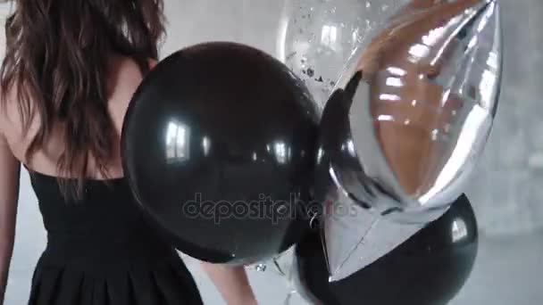 Fille en robe noire va avec des ballons et regarde la caméra — Video