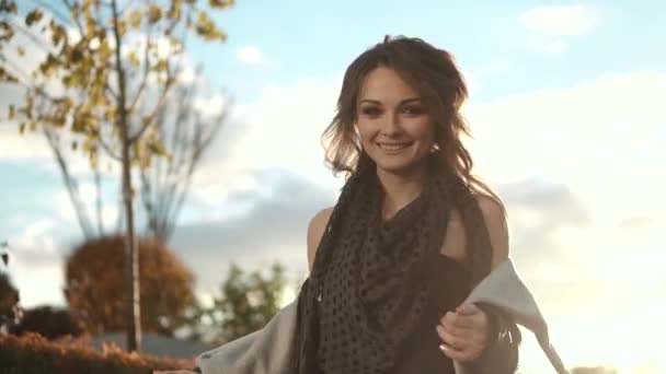 Charming young woman walks through the autumn city in a coat and smiles. — Stock Video