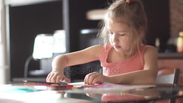 Child of 6 years draws houses sitting at a table. little girl in the morning sun — Stock Video