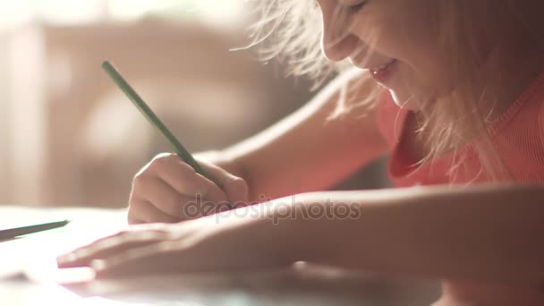 Dziecko 6 lat rysuje domy siedzi przy stole. mała dziewczynka w rannym słońcu — Wideo stockowe
