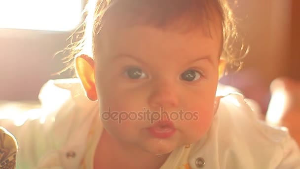 Little kid lies on the bed in the sun. mom kisses her newborn baby. kind bright frame — Stock Video