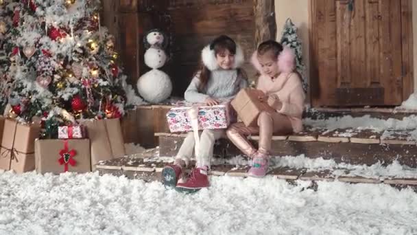 Weihnachten oder Neujahr. Kinder betrachten Geschenke in wunderschönen Weihnachtsboxen. zwei kleine Mädchen auf einem Weihnachtsbaum Hintergrund — Stockvideo