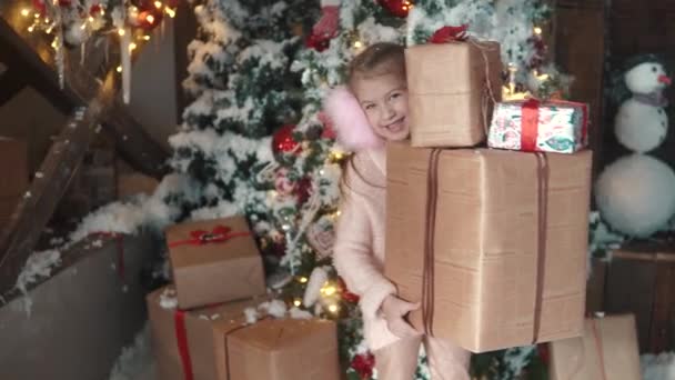 Natal ou ano novo. menina segurando em mãos uma caixa com presentes e sorrisos slyly. a criança recebeu muitos presentes no Natal — Vídeo de Stock