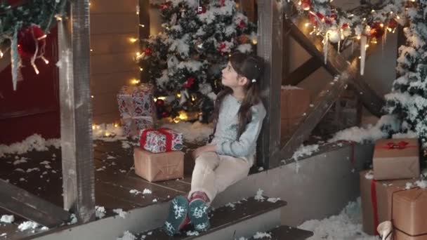 Χριστούγεννα ή Πρωτοχρονιά. κοριτσάκι που κρατάει στα χέρια ένα κουτί με δώρα και χαμόγελα πονηρά. το παιδί έλαβε πολλά δώρα για τα Χριστούγεννα — Αρχείο Βίντεο