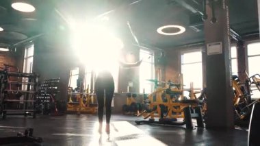 Çalışma dışarı spor eğitim kadın atlanıyor. Genç kadın ip atlama uygun. Spor giysileri içinde güneş ışığı kızı