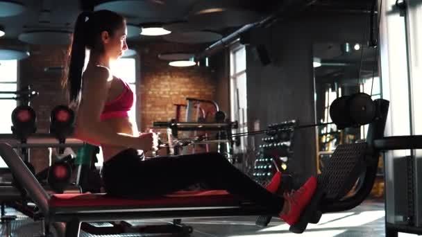 Képzés az edzőteremben fitness-lány. vonzó sportoló csinál egy gyakorlása a tornateremben edzés veszélyforrást. lány az izmok, a hát a gyakorlat végzése — Stock videók