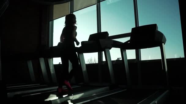 Καρδιο για τον διάδρομο. ασκήσεις για την απώλεια βάρους. σιλουέτα ενός κοριτσιού σε διάδρομο. νεαρό κορίτσι σπορ τρέξιμο στο διάδρομο στο γυμναστήριο. αθλητής σε αθλητικά είδη — Αρχείο Βίντεο