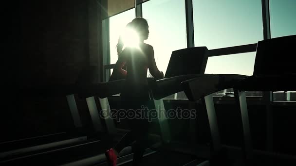 Cardio na esteira. exercícios para perda de peso. silhueta de uma menina em uma esteira. jovem menina desportiva correndo na esteira no ginásio. atleta em sportswear — Vídeo de Stock