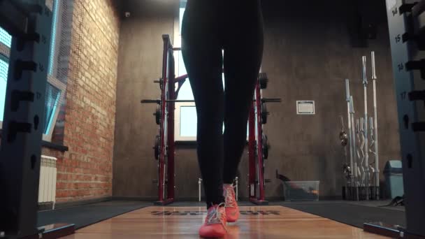 Mladá sportovkyně dělat sedy-lehy s činka v posilovně. dívka v sportswear dělá silový trénink na nohy — Stock video