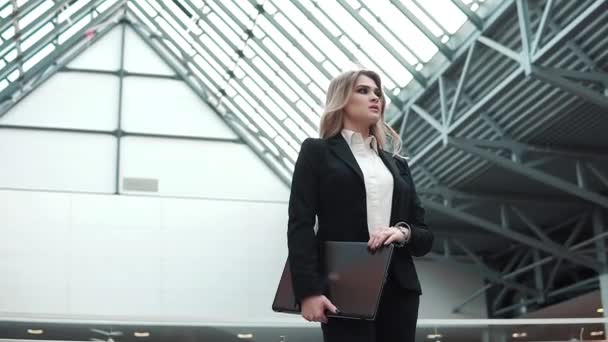 Vrouw in een bedrijf pak met een laptop in handen op een moderne zakelijke gebouw achtergrond. zakenvrouw verwacht een client of business partner — Stockvideo