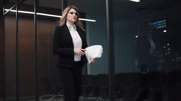 ビジネスの女性は、オフィスのガラスのパーティション上の背景と廊下を歩きます。オフィスでビジネス スーツ女性 — ストック動画