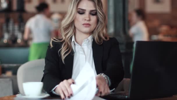Молодая деловая женщина, работающая в кафе. девушка в деловом костюме работает с бумагами — стоковое видео
