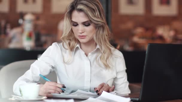 Goed verzorgd mooie zakenvrouw werken in een café zitten aan de tafel. het meisje Manager de documenten ingevuld en werkt op een laptop — Stockvideo