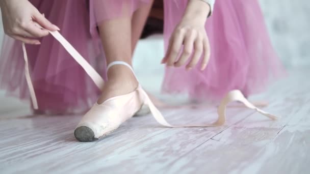 Bailarina a amarrar os pointes. bailarina de balé usando sapatos de balé no estúdio — Vídeo de Stock