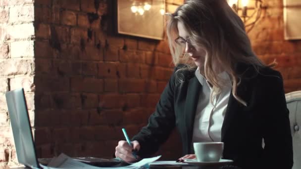 Business woman working with documents in the office in the strength of a loft. a girl in business clothes and wearing glasses. business make-up and hairstyle — Stock Video
