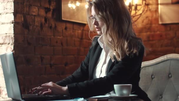 Бізнес-леді, що працює в кафе на ноутбуці. дівчина в діловому костюмі, що працює з документами в неформальній обстановці — стокове відео